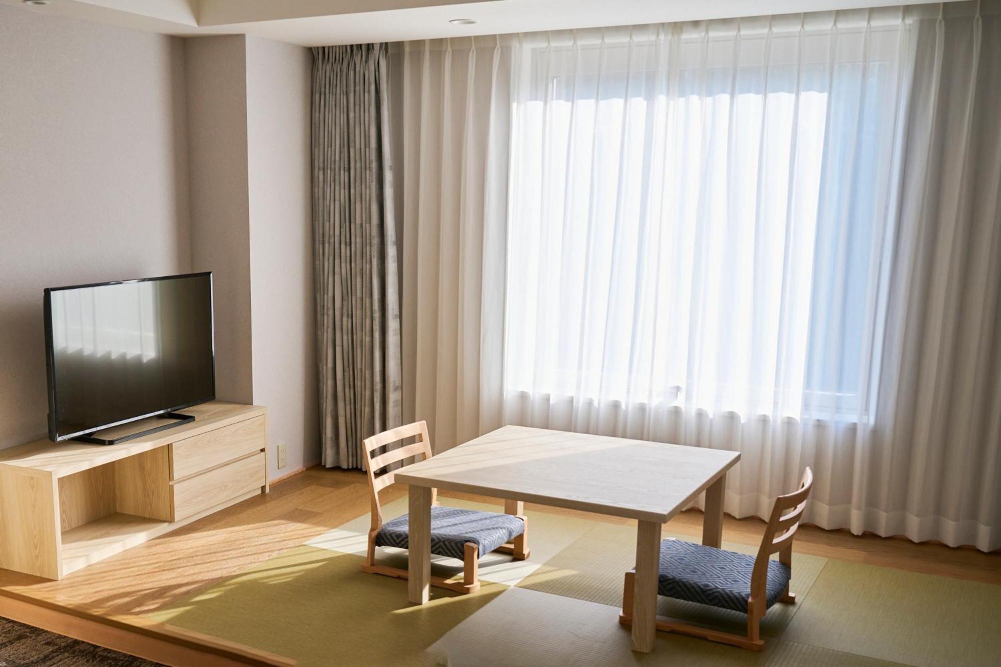 Narita Tobu Hotel Airport Exterior photo A room with a table, a chair, a sofa, a tv, and a dresser